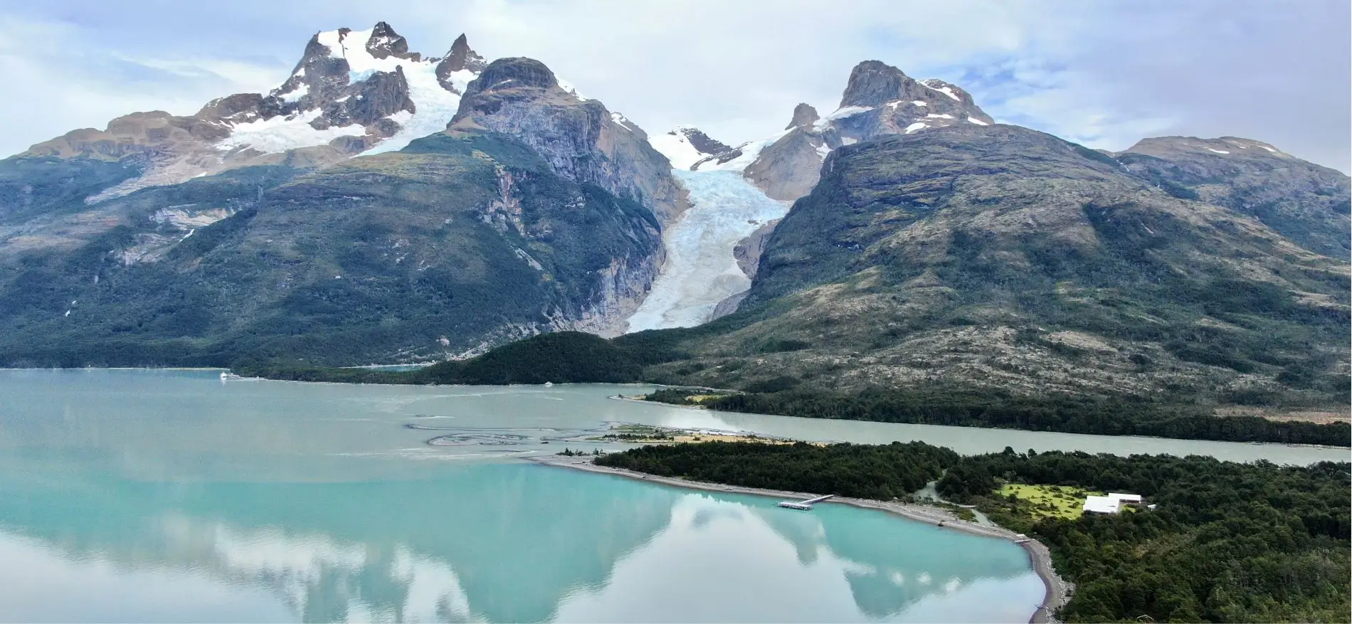 Vista panorámica del Monte Balmaceda Lodge rodeado de naturaleza con el impresionante Glaciar Serrano al fondo en la Patagonia.