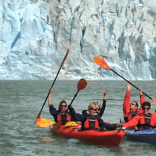 Group of tourists in kayaks paddling through the calm waters of Serrano Lagoon in front of the Serrano Glacier in Patagonia.