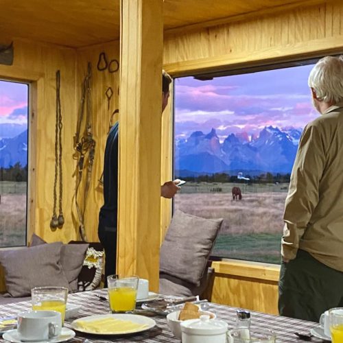 Dining room windows at Vista al Paine refuge showing a direct panoramic view of the Torres del Paine massif.
